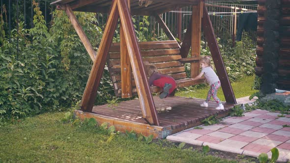 Children Swing on a Large Wooden Swing, Near the Summer House, They Play