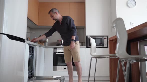 Man Cleans Up Kitchen Puts Dishes in Dishwasher