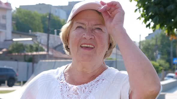 Portrait of a happy woman of retirement age, a pensioner corrects a cap from the sun.