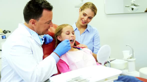 Dentist examining a young patient with tools