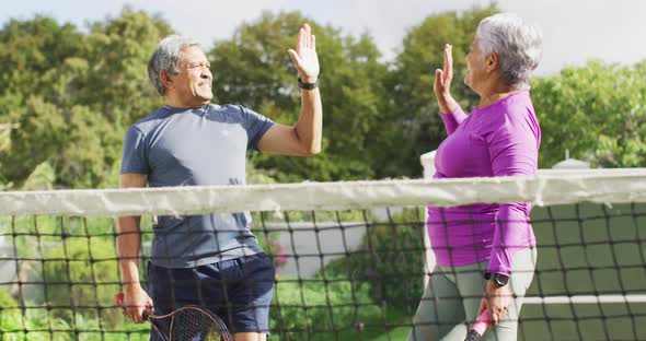 Video of happy biracial senior couple clapping hands during tennis training