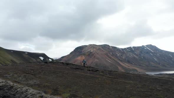 Following Man Running on Trail in Volcanic Landscape
