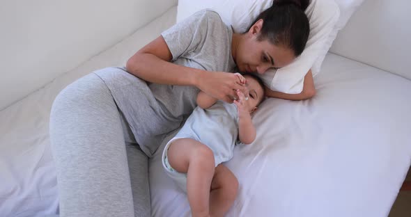 Young loving mother lying with her son on bed at home - Family and motherhood concept