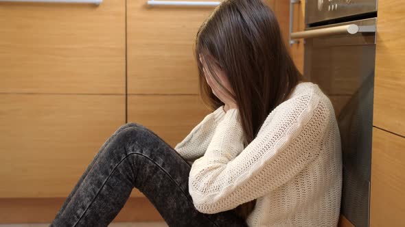 Crying Teenage Girl Sitting on Floor at Kitchen