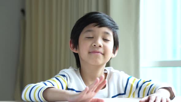 Asian Child Knocking His Hands On The Table.