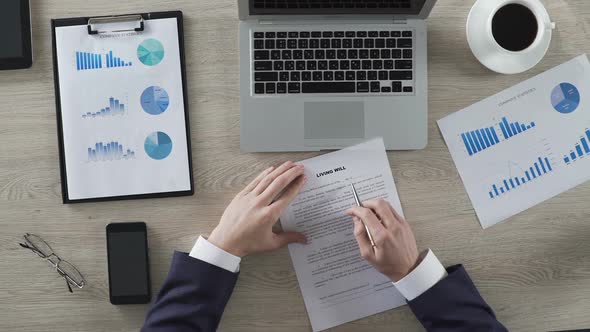 Businessman Reading Living Will Conditions and Signing Paper, Top View