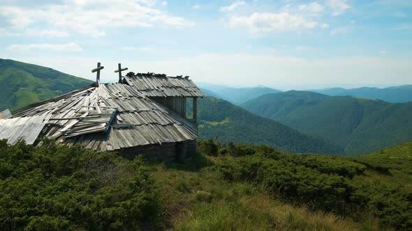 Summer mountain landscape with old forsaken tourist shelter on grassy hills and distant peaks