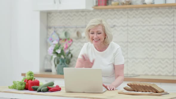 Attractive Senior Old Woman Doing Video Call on Laptop in Kitchen