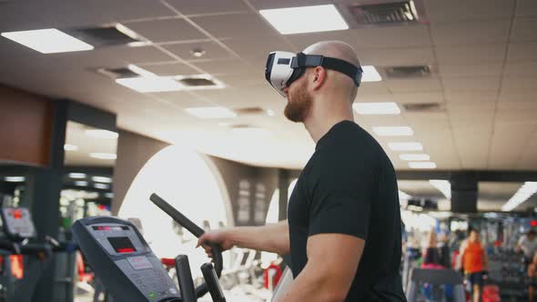 Young Strong Man Exercising on Treadmill at the Gym Wearing VR Glasses