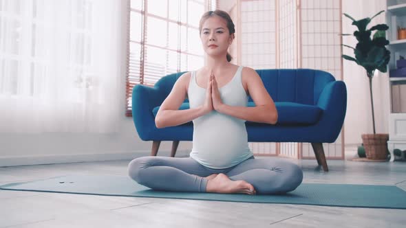 Asian pregnant woman doing yoga exercise at home.