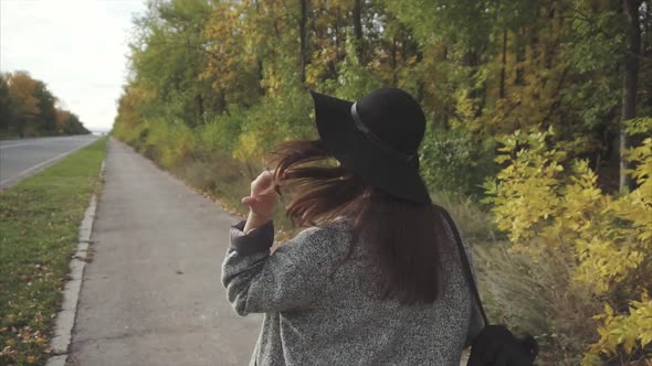 Young Pretty Woman in Black Hat and Glasses Walking Down the Autumn Street