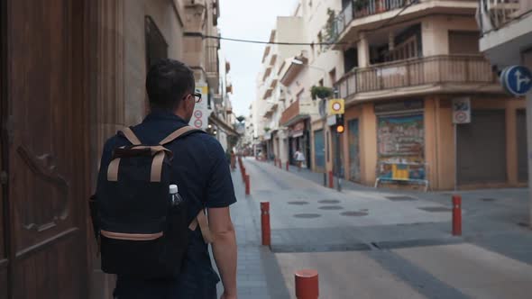 Male City Dweller Is Walking in Narrow Lane with Small Crossroads in Daytime