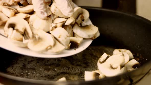 Cooking food concept. Cook fry the mushrooms in a frying pan. Slowmotion close up of chef mixing mus