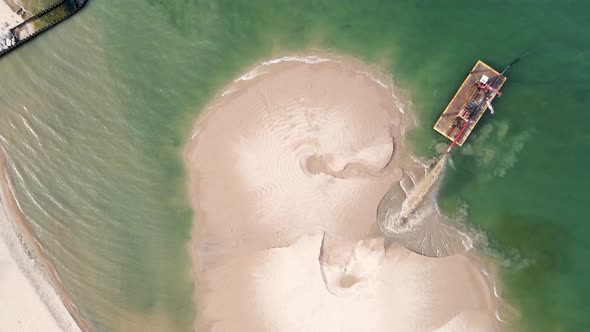 A bird's eye view of the beach being filled in with sand in summer.