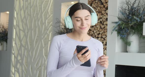 Happy Cheerful Young Woman Dancing Alone at Home and Using Smartphone for Listening Music