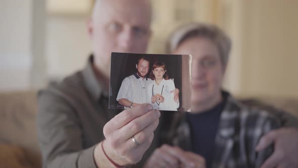 Portrait of Senior Couple Showing Them Photograph To the Camera When Man and Woman Was Very Young