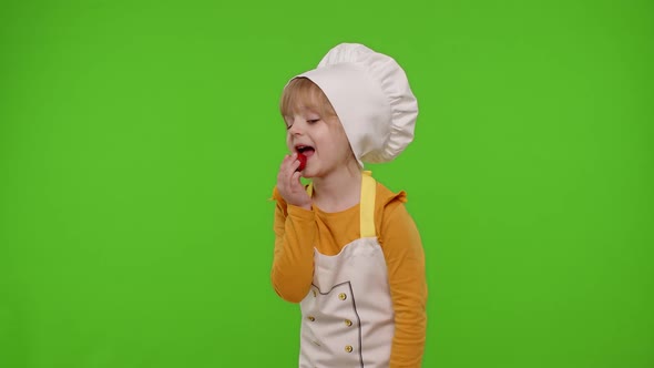 Child Girl Dressed As Cook Chef Baker in Apron Eats Delicious Fresh Strawberries and Dances