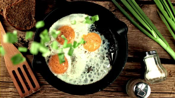 Super Slow Motion Chopped Green Onions Drops Into the Pan with Fried Eggs