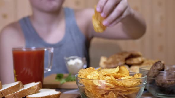 Hungry Kid Hand Takes Crispy Golden Potato Chips From Plate