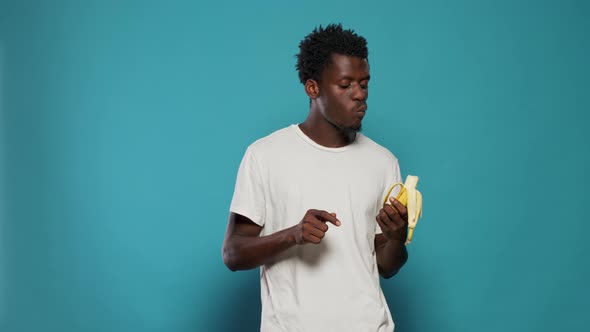 Portrait of Casual Adult Eating Banana on Camera in Studio