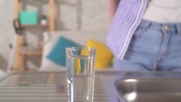 Young Woman Pours Clean Tap Water Into a Glass