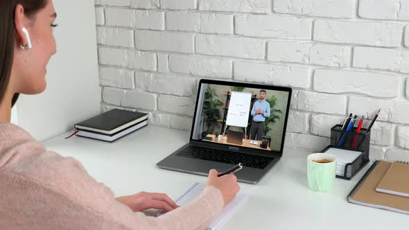 Businesswoman at Home Office Writes in Notebook Listen Online Video Call Laptop