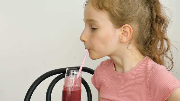 Sweet Little Girl Drinks Raspberry Smoothie and Smiles