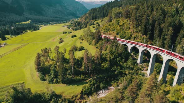 Aerial View of a Moving Red Train Along the Landwasser Viaduct in Swiss Alps