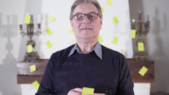 Portrait of Confident Old Caucasian Man in Eyeglasses Reading Note, Looking at Camera and Smiling