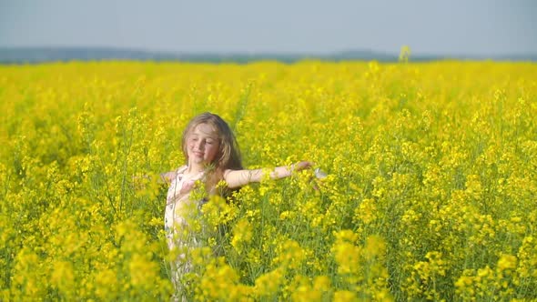 Girl on the Field Among Canola Flowers