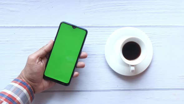 Top View of Man Hand Holding Smart Phone and Drinking Tea