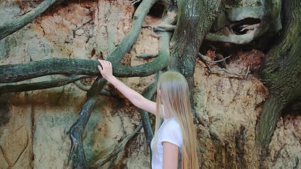 Young Blonde Woman Looking on Exposed Tree Roots in Natural Loess Ravine