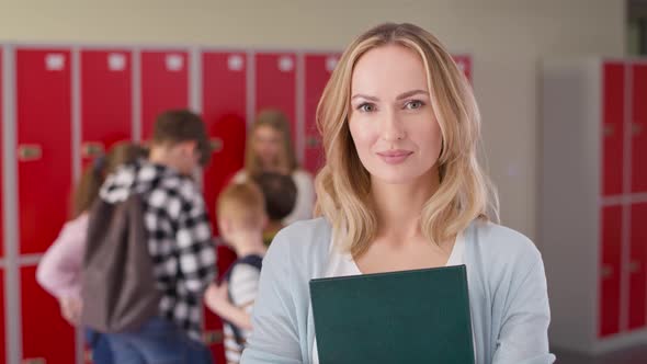 Video portrait of smiling teacher standing in the school corridor.