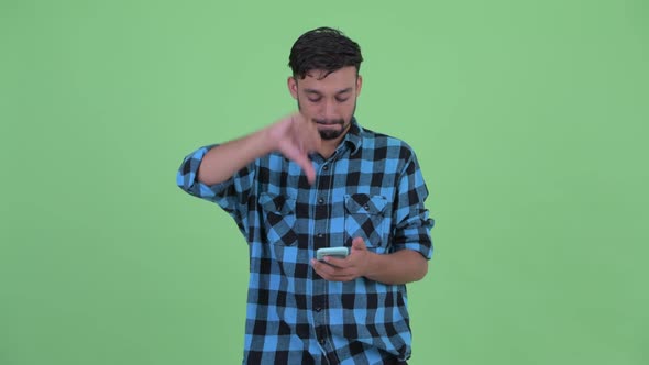 Stressed Young Bearded Persian Hipster Man Using Phone and Getting Bad News