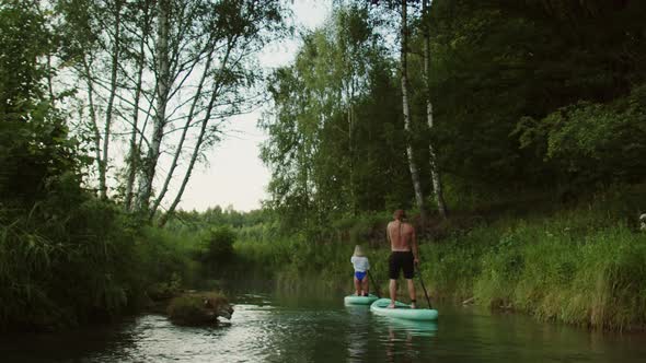 Couple of Surfers in Lake Paddling on Surfing Boards One After the Other People Rowing Standing on