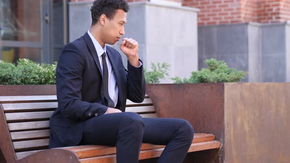 Coughing African Businessman Sitting on Bench