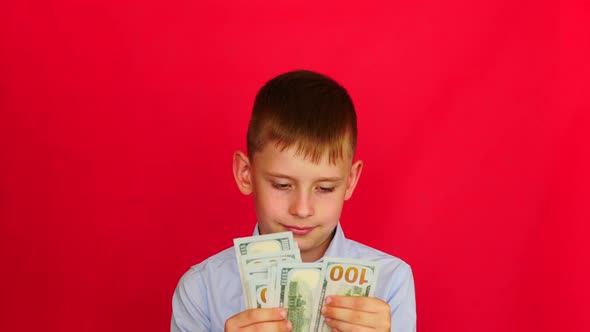 portrait of a cheerful caucasian boy 7-8 years old counting American paper bills of 100 dollars. Stu