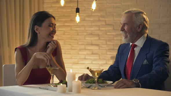 Pretty Woman Flirting With Elderly Millionaire During Dinner in Restaurant