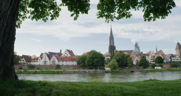 Panoramic shot of the skyline of Ulm, Germany. Cameraes slowly in, tree in the foreground, Danube in