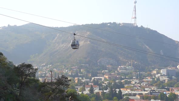 Cableway Car Hanging Above the Tbilisi City in Georgia with the View of Old Buildings on Background