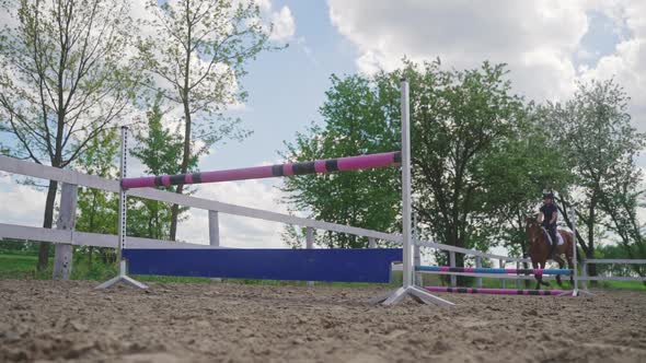 Woman Rider On A Horse Leaping Over A Fence In Sandy Parkour Equestrian Events