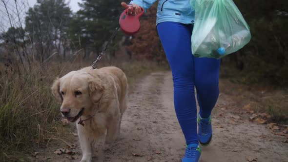 Fit Female Cleaning Up Litter in Forest During Jog