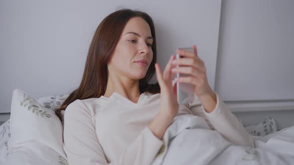 Woman Using Smartphone on Bed