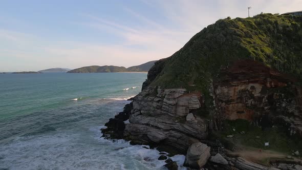 Flying by ocean cliff, waves splashing aganst rocks, Brazil shoreline