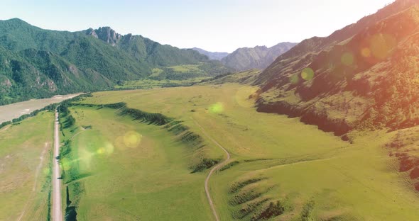 Aerial Rural Mountain Road and Meadow at Sunny Summer Morning. Asphalt Highway and River.