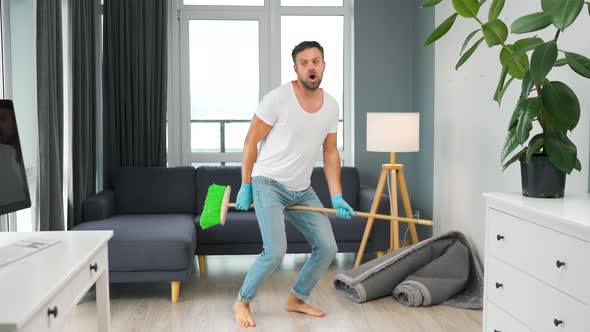 Man Cleaning the House and Having Fun Dancing with a Broom