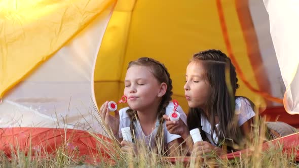 Two Little Girls are Sisters They are Sitting in a Tent and Blowing Bubbles