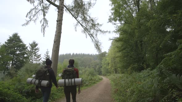 Couple carrying rucksacks and walking through trail