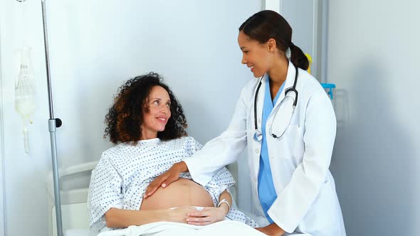 Doctor examining pregnant woman in ward