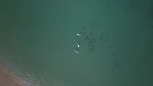 Descending aerial view of paddle boarders enjoying a sunny day in Oahu